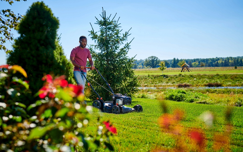 Man pushing a Senix lawn mower powered by a E550 Briggs & Stratton engine.