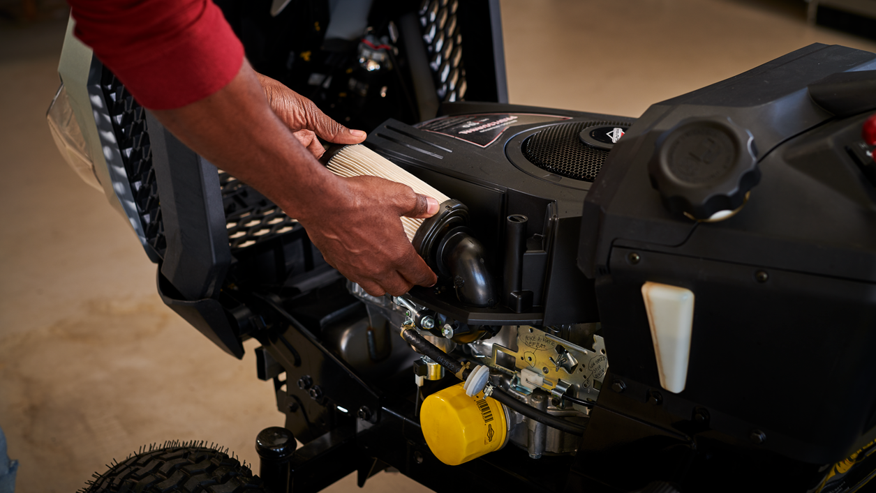 A man servicing a Briggs & Stratton ride mower engine.